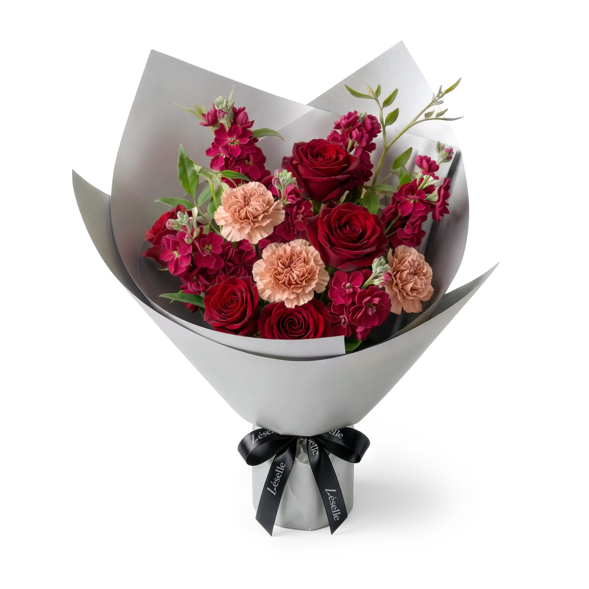 A fresh flower bouquet wrapped in silver paper with a black ribbon, featuring red roses, peach carnations, red stocks, and green foliage, set against a transparent background.